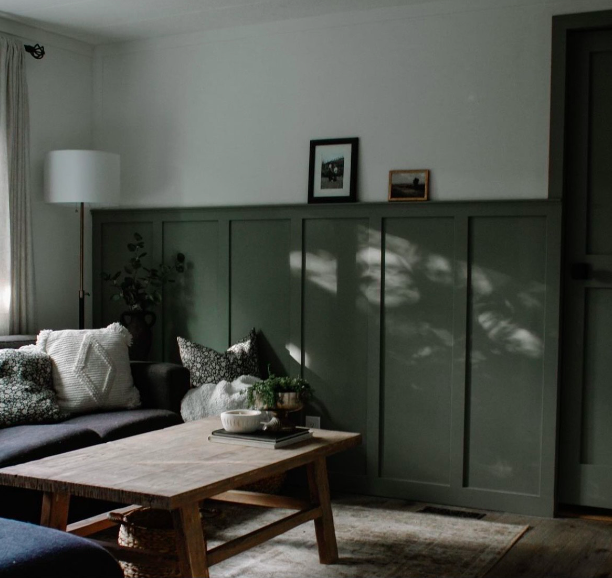 Renovated living room with green wall panelling and custom trim